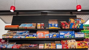 A shelf stocked with various snack items including Honey Buns, popcorn, and boxed snacks. - Economy Suites - Fairgrounds (Tulsa)
