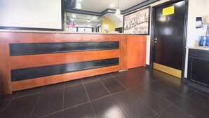A reception area with a wooden counter, a black door, and a sign on the wall.