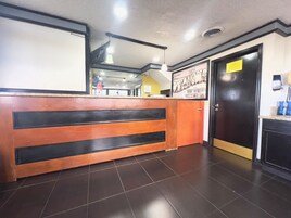 Un área de recepción con un mostrador de madera, una puerta negra y un cartel en la pared.