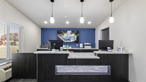 A reception area with a dark wood reception desk, a blue accent wall, and a large digital clock. - SureStay Hotel by Best Western Twin Falls (Twin Falls)