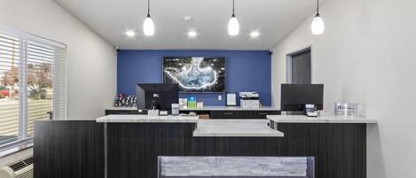 A reception area with a dark wood reception desk, a blue accent wall, and a large digital clock.