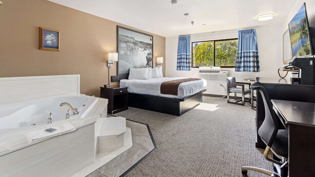 A hotel room with a large bed, a separate bathroom with a bathtub, a desk, and a chair. - SureStay Hotel by Best Western Twin Falls (Twin Falls)