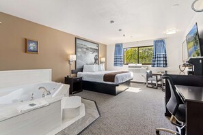 Habitación de hotel con una cama grande, baño independiente con bañera, escritorio y una silla.