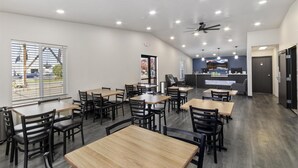 A modern restaurant with wooden tables and black chairs, a counter with a menu, and a ceiling fan. - SureStay Hotel by Best Western Twin Falls (Twin Falls)
