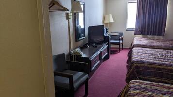 Ein Hotelzimmer mit Schreibtisch, Stuhl, Fernseher und zwei Betten.