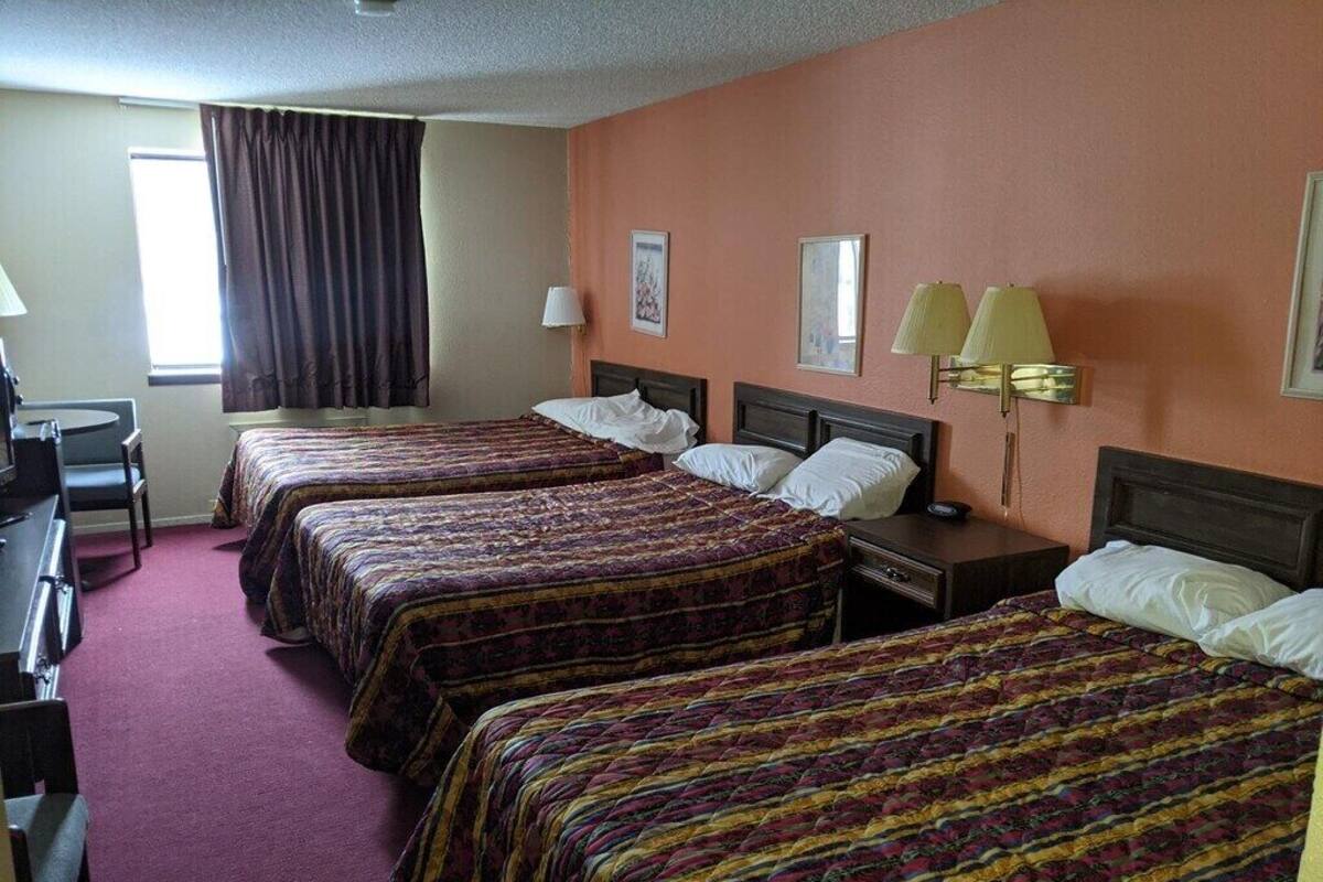 Een hotelkamer met drie bedden, een bureau en een stoel.