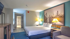 A hotel room with a large bed, two bedside lamps, a chair, a desk, and a cityscape painting on the wall. - Super 8 by Wyndham Rockford I-90/Casino District (Rockford)