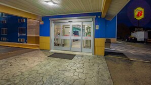 A building entrance with a glass door, a parking lot, and a Super 8 sign. - Super 8 by Wyndham Rockford I-90/Casino District (Rockford)