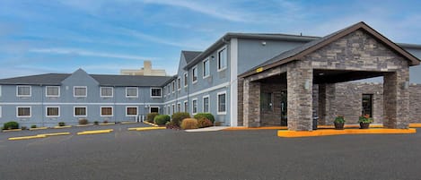 A hotel with a stone entrance, multiple windows, and a parking lot.