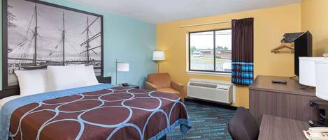 A hotel room with a bed, a desk, a chair, a window with curtains, a lamp, and a painting on the wall.