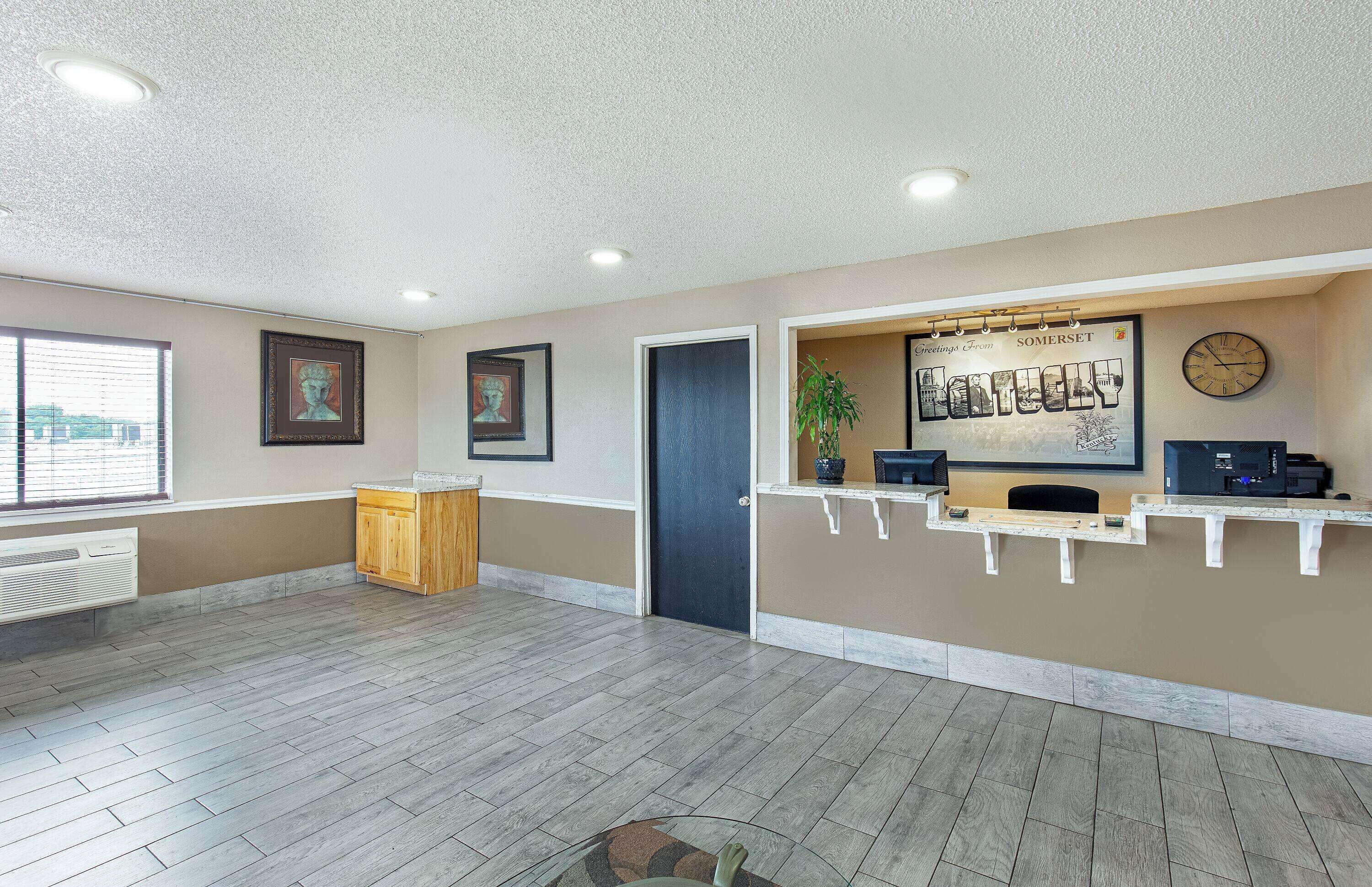 A reception area with a wooden counter, framed artwork, a clock, and a plant.