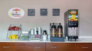 A breakfast station with a coffee machine, fruit display, and coffee mugs. - Super 8 by Wyndham Somerset (Somerset)