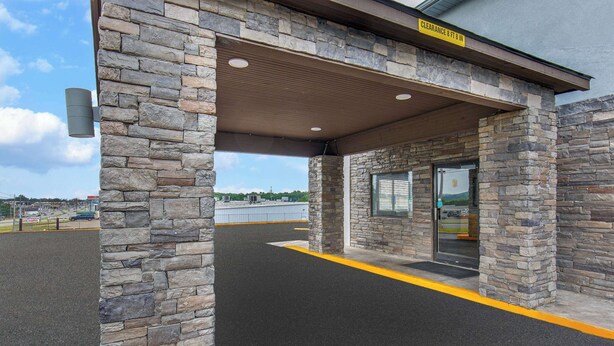 A stone building with a covered entrance and a sign indicating a clearance of 8 ft 8 in. - Super 8 by Wyndham Somerset (Somerset)