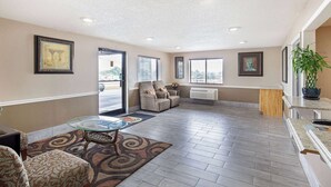 A spacious living area with a glass coffee table, patterned rug, and two armchairs. - Super 8 by Wyndham Somerset (Somerset)