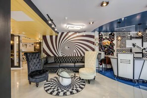 A modern interior with a black and white patterned wall, a tufted black sofa, a white armchair, and a record wall.
