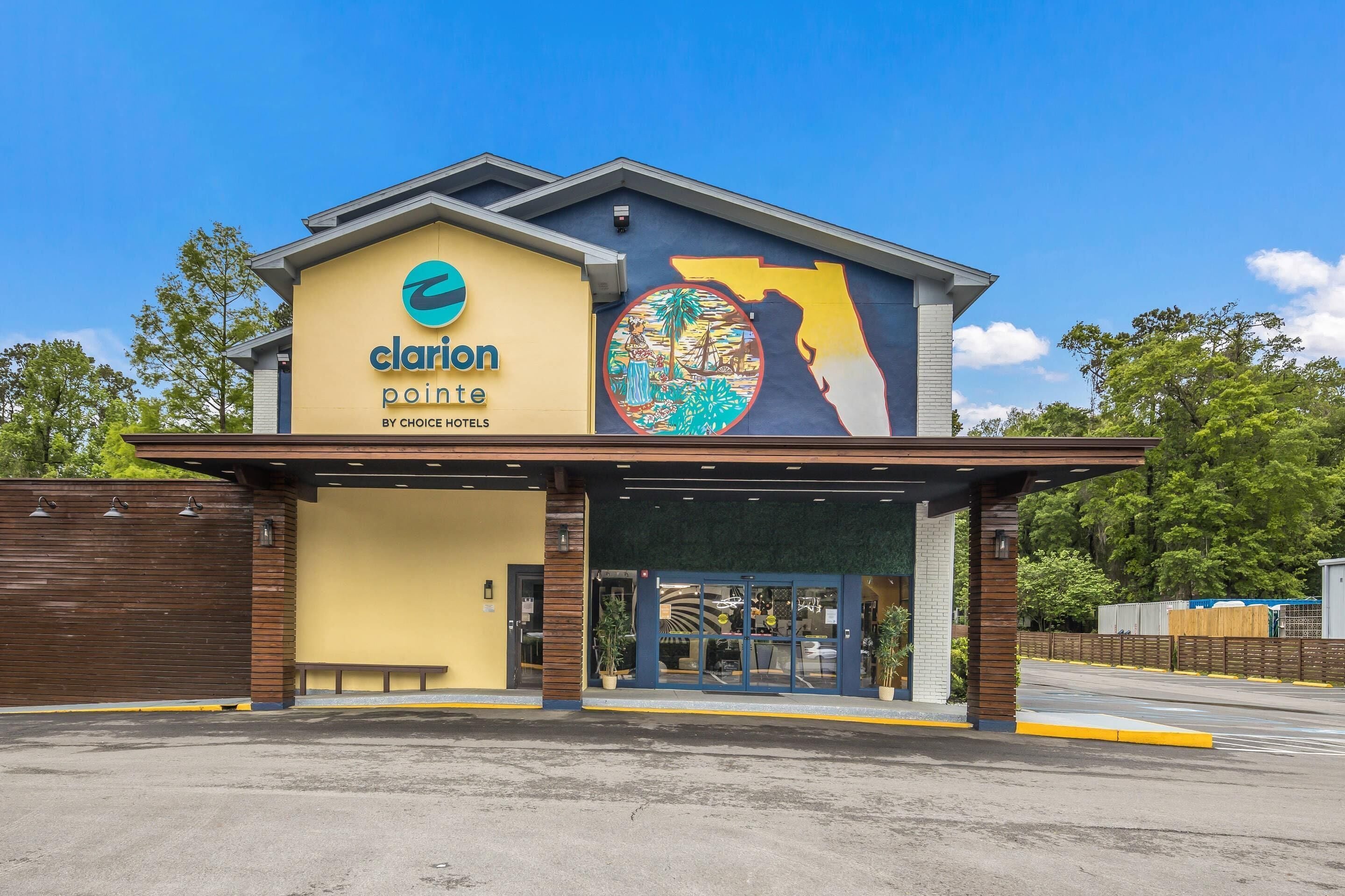 Et hotel med et stort skilt der viser 'clarion pointe' og et muralmaleri af et håndaftryk på siden.