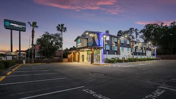 A hotel with a modern design, a parking lot, and a clear sky.