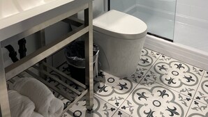 A modern bathroom with a white sink, a glass shower enclosure, and patterned floor tiles. - Clarion Pointe Tallahassee-State Capitol (Tallahassee)