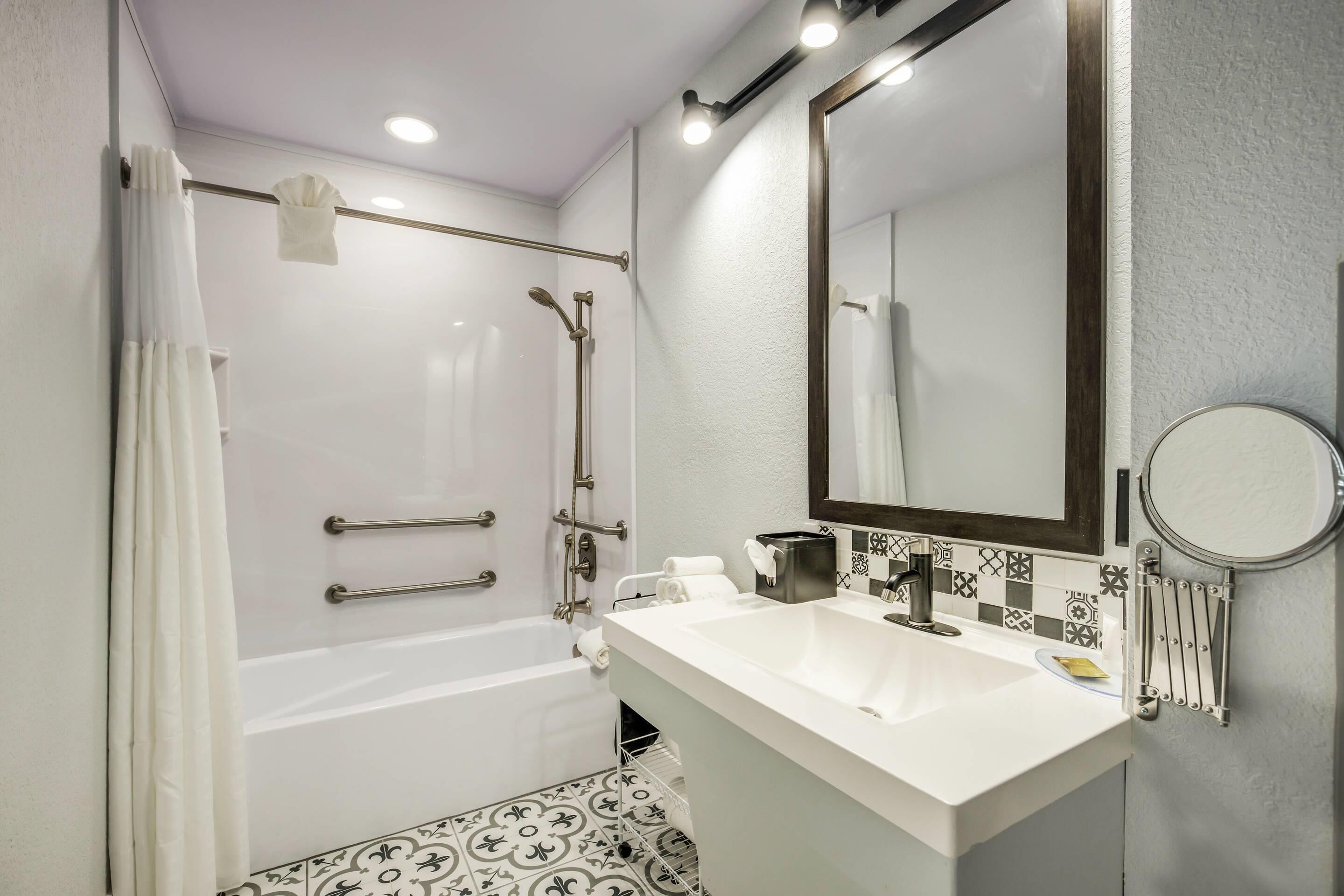 A modern bathroom with a bathtub, a shower, a sink, and a mirror.