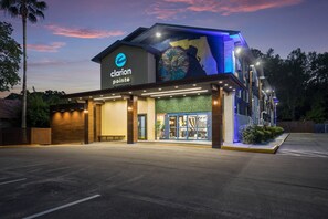 A hotel with a modern facade, a prominent logo, and a large mural on the side.
