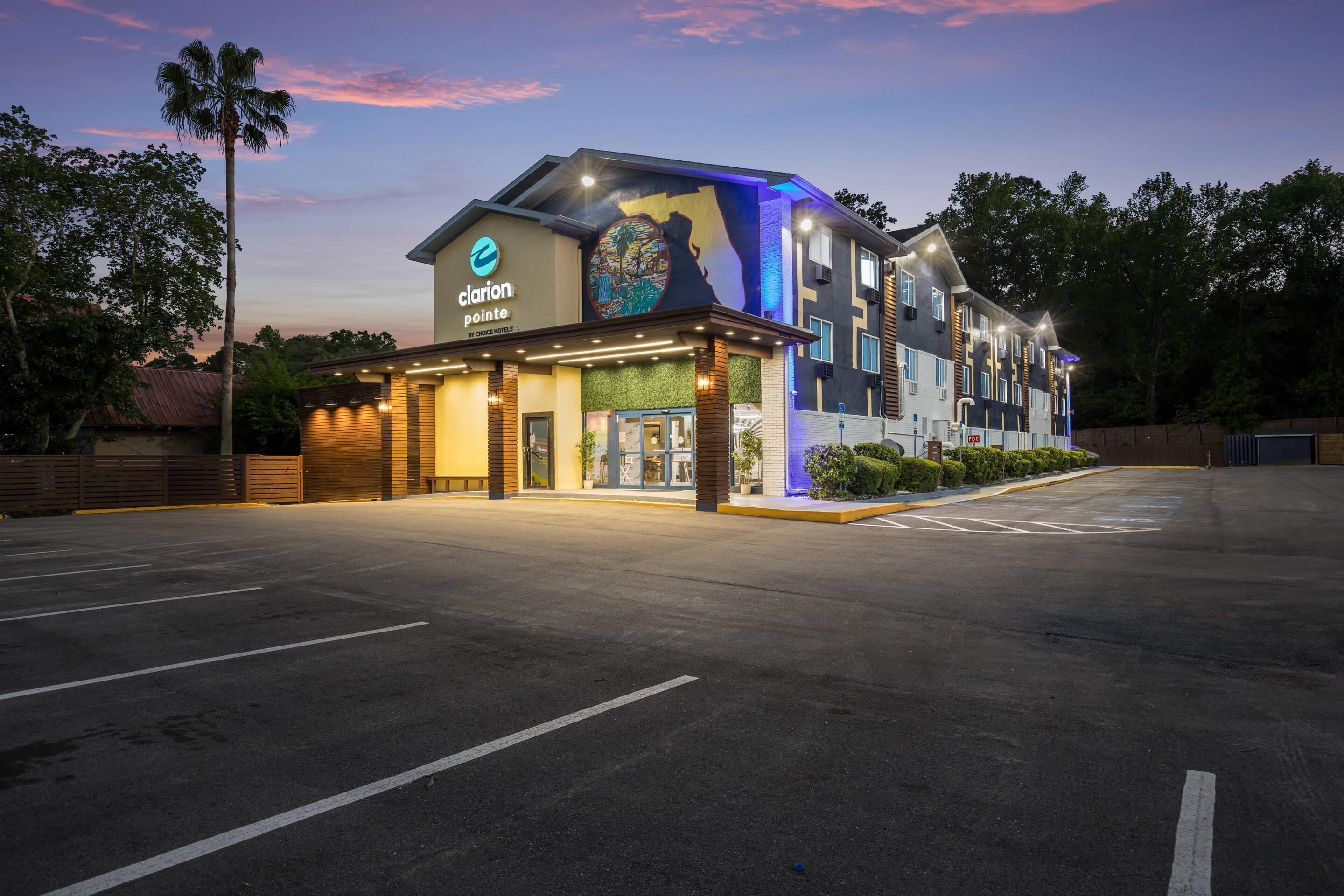 A hotel with a modern design, a large sign, and a parking lot.