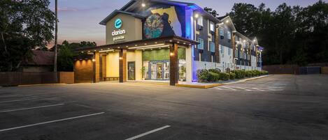 A hotel with a modern design, a large sign, and a parking lot.