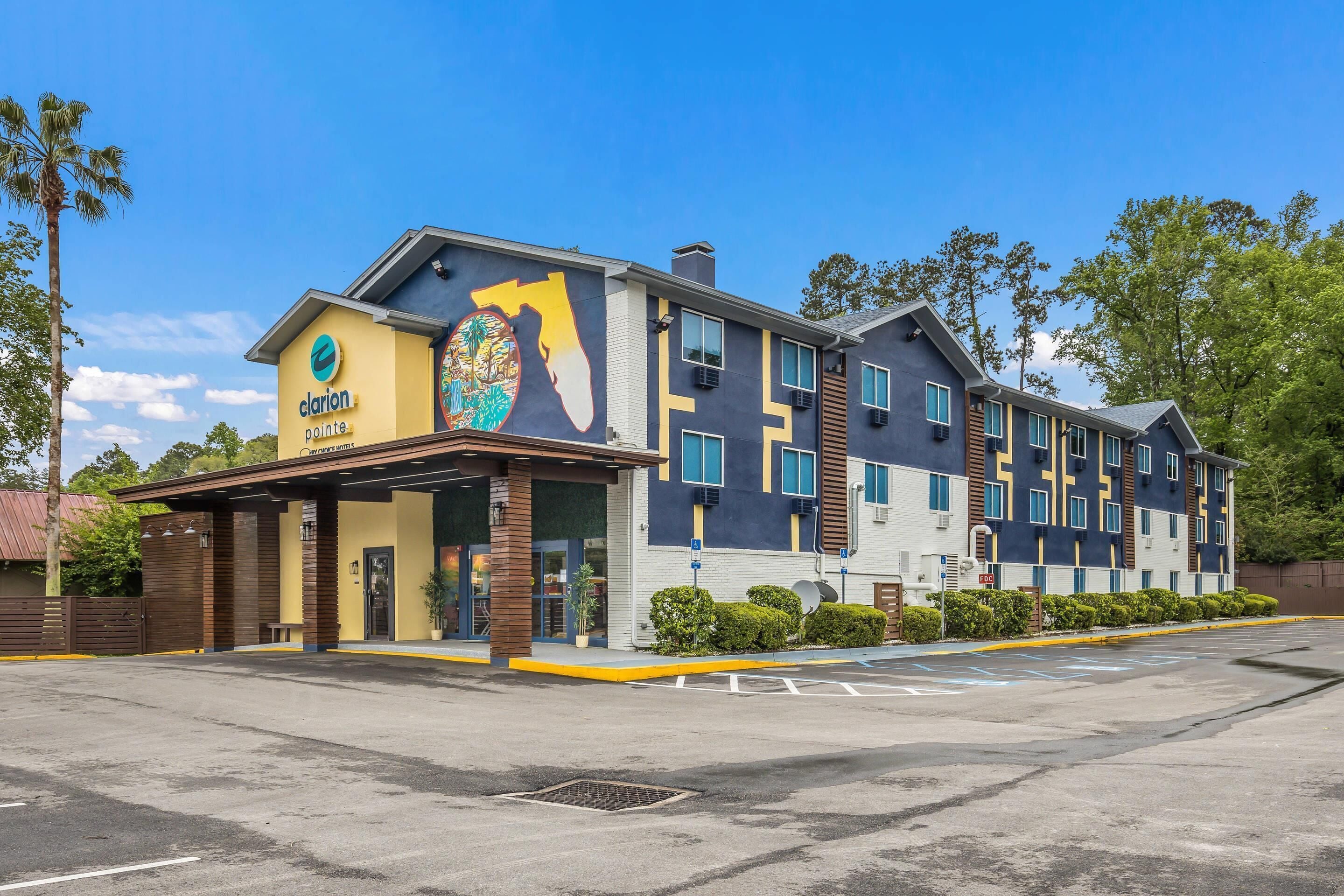 A hotel with a modern design, featuring a large mural on the facade, multiple windows, and a covered entrance area.