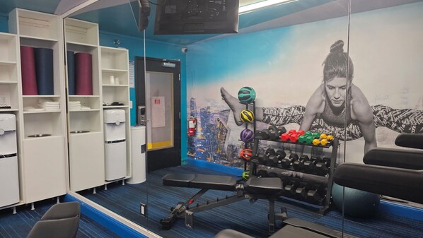 A gym with exercise equipment, a wall mural, and storage shelves. - Clarion Pointe Tallahassee-State Capitol (Tallahassee)