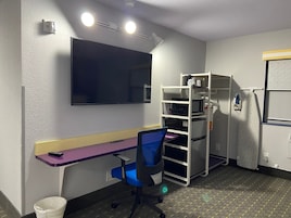 Una habitación compacta con escritorio, silla y microondas integrado.