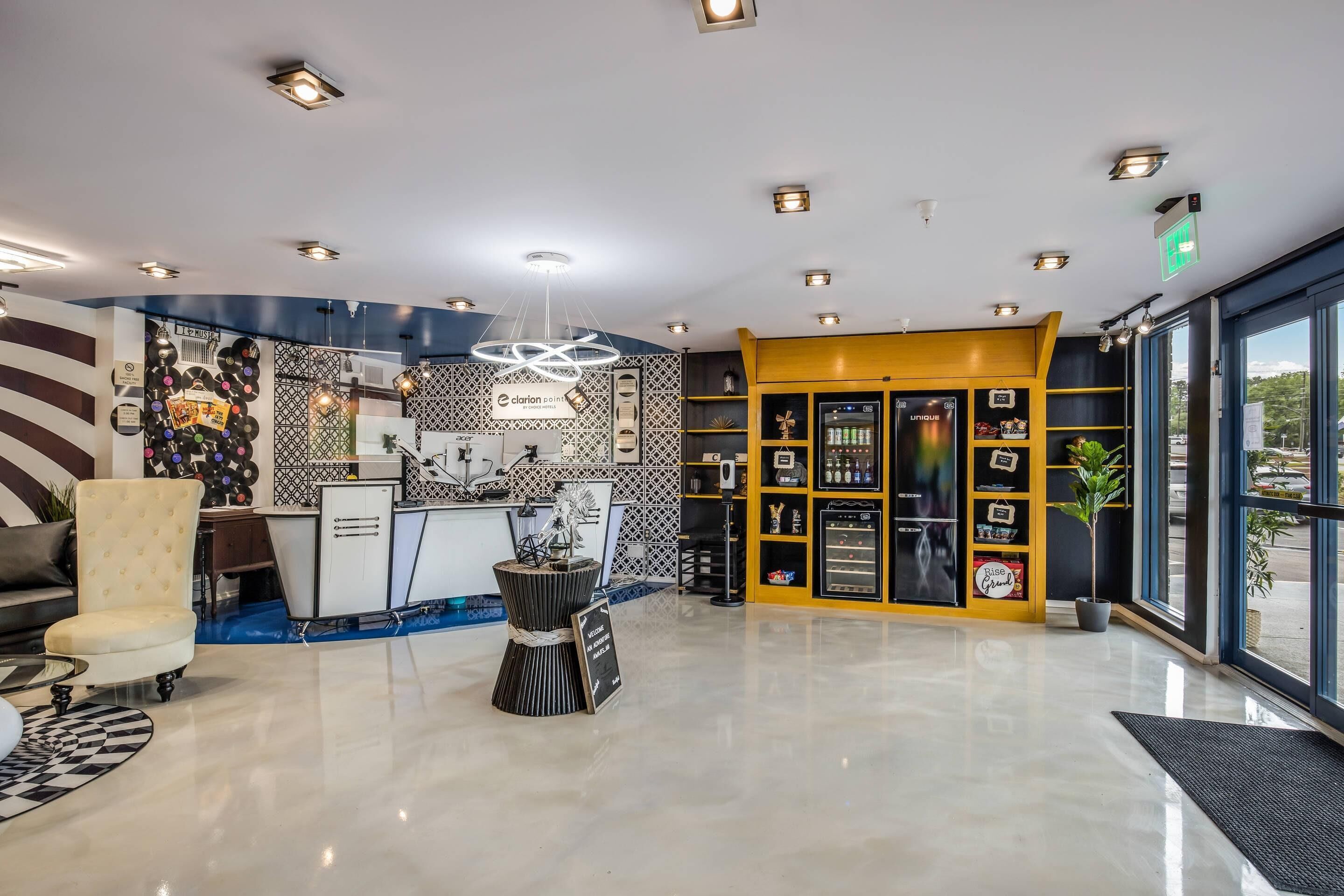 A hotel lobby with a reception desk, a wall of vinyl records, a unique sculpture, and a minibar.
