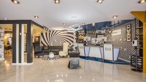 Un moderno vestíbulo de hotel con una zona de estar central, una recepción y un muro con diseño.