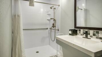 A modern bathroom with a walk-in shower, a white sink, and a mirror.