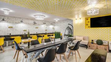Un interior moderno con techo estampado, una mesa de comedor central, sillas amarillas y un sofá.