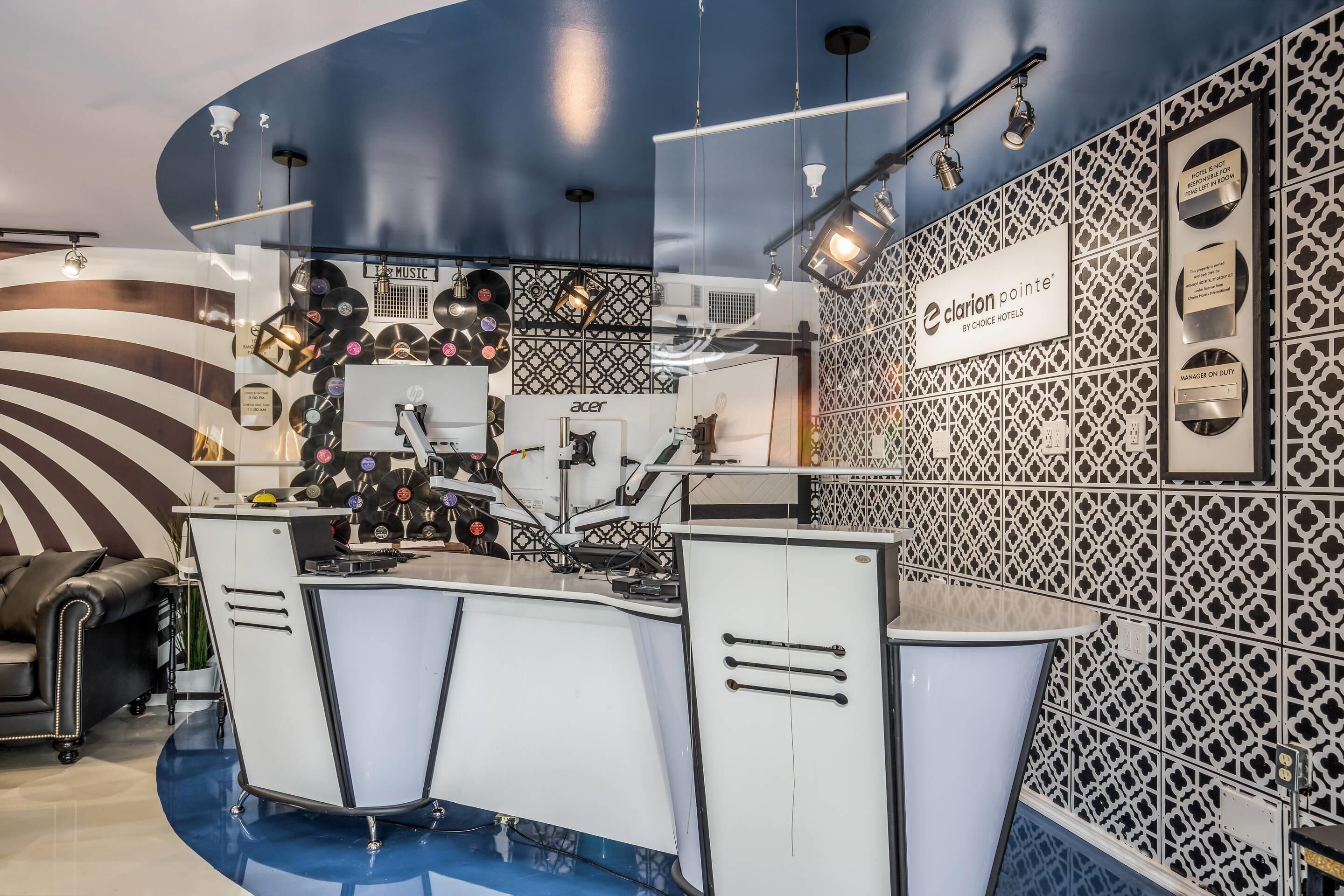 A modern hotel reception area with a curved counter, a music-themed wall, and a patterned wall with hotel signage.