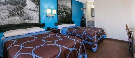 A hotel room with two beds, a desk, a chair, a coffee maker, and two wall-mounted lamps.