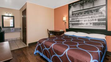 Habitación de hotel con cama, escritorio, silla, mesita de noche, lámpara y ventana grande con vista a una cascada.