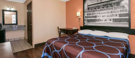 A hotel room with a bed, a desk, a chair, a nightstand, a lamp, and a large window with a waterfall view.
