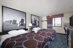Ein Hotelzimmer mit einem großen Bett, einem Schreibtisch mit Fernseher und zwei großen gerahmten Bildern an der Wand.