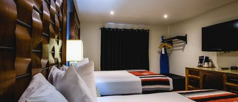 Une chambre d’hôtel avec deux lits, un téléviseur à écran plat, un bureau avec une machine à café et une armoire.