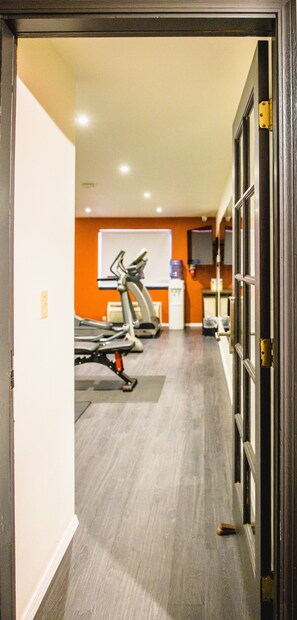 A gym with exercise equipment, a whiteboard, and a water dispenser. - Coyote South (Santa Fe)