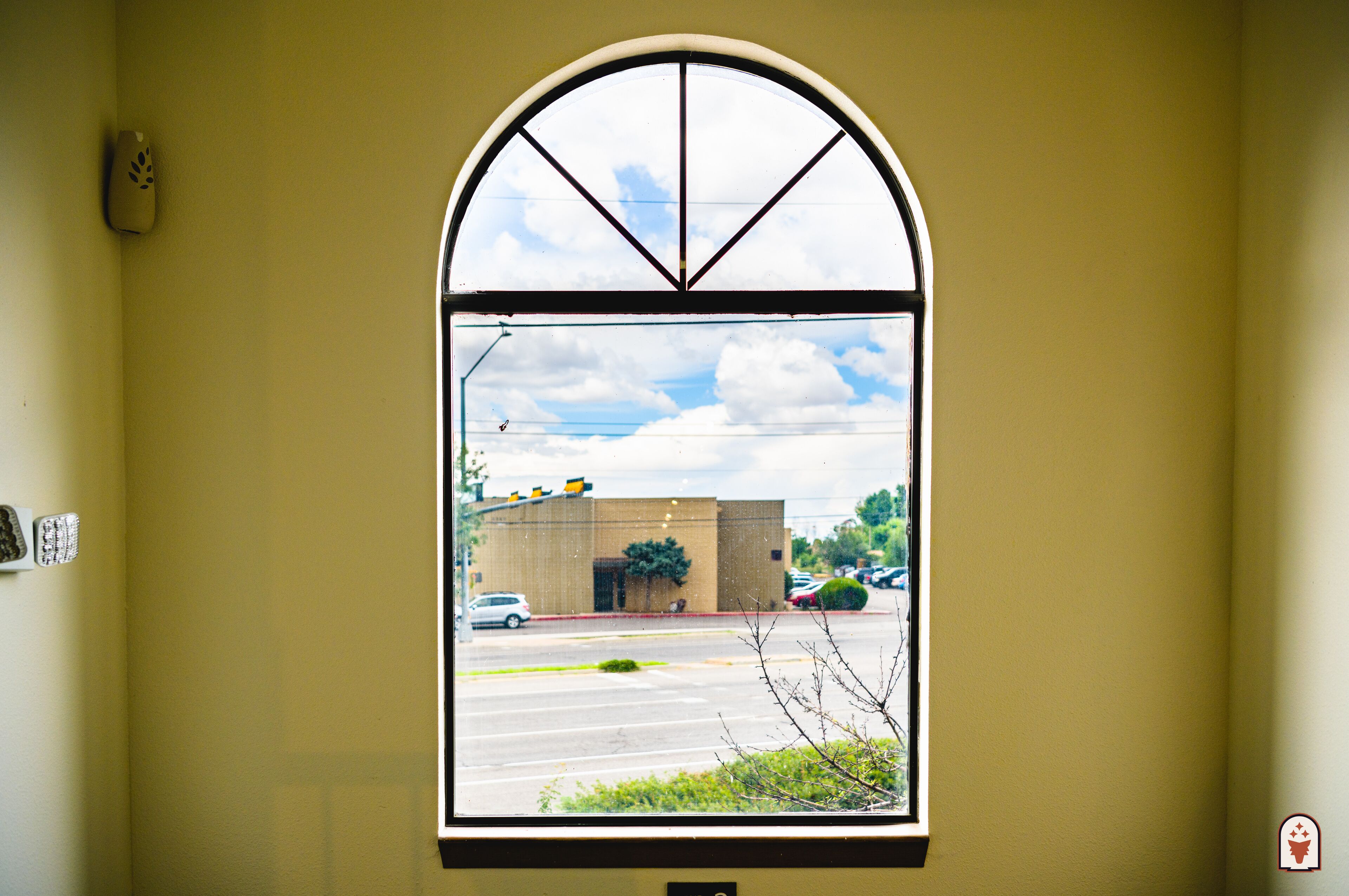 Una ventana con vista a un edificio y un estacionamiento.
