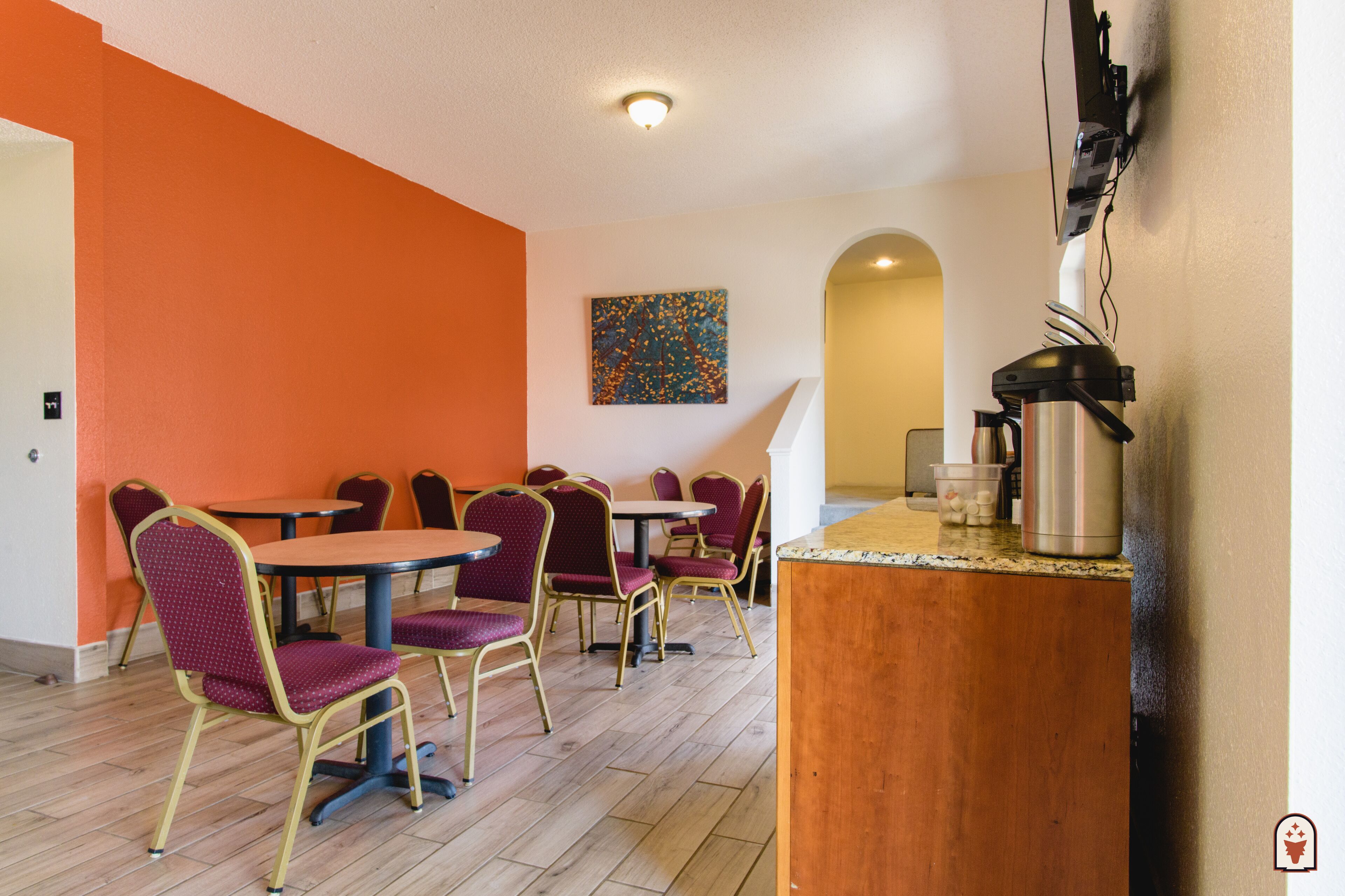 Un espace repas avec des murs orange, des tables rondes et des chaises violettes.