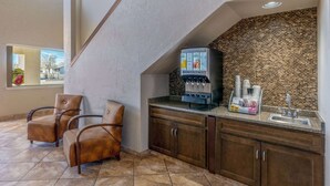 A modern kitchen with a coffee machine, two leather chairs, and a brick backsplash.