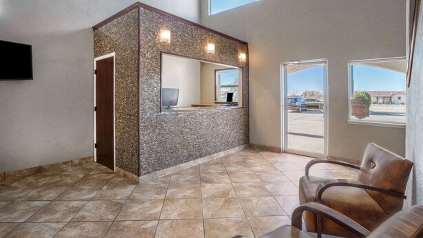 A reception area with a stone wall, a reception desk, and two leather chairs.
