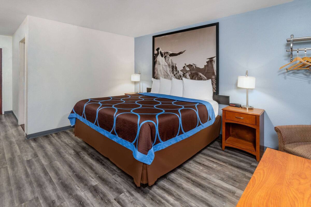 Une chambre d’hôtel avec un grand lit, une table de chevet en bois, un bureau et une chaise.