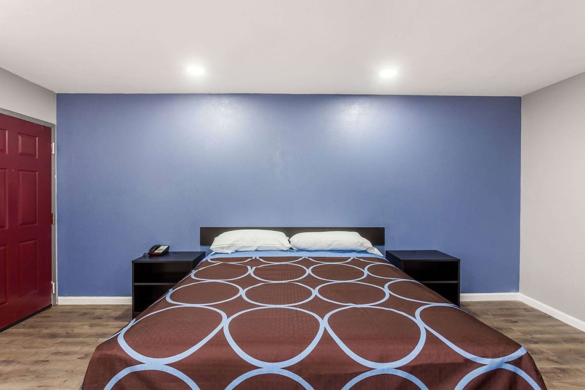Ein Schlafzimmer mit einem Bett, einem Nachttisch, einer roten Tür und einer blauen Wand.