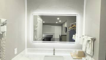 Un baño con un espejo grande, un lavabo y un perchero para toallas.