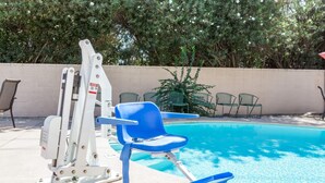 Zona de piscina con trampolín, sillas reclinables azules y una pared de hormigón.