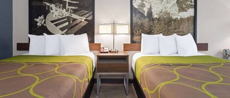 Une chambre d’hôtel avec deux lits, une table de chevet, une lampe et deux grandes œuvres d’art mural représentant l’espace et des montagnes.