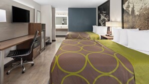 Habitación de hotel con escritorio, dos camas, televisor y ventana grande.